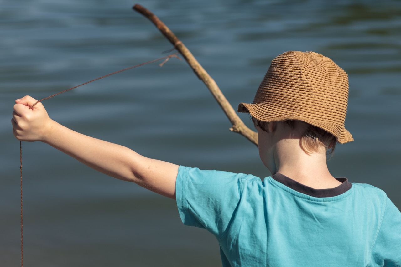 child with a self-made fishing rod from a branch and a line on a lake -  Photo #1340 - motosha