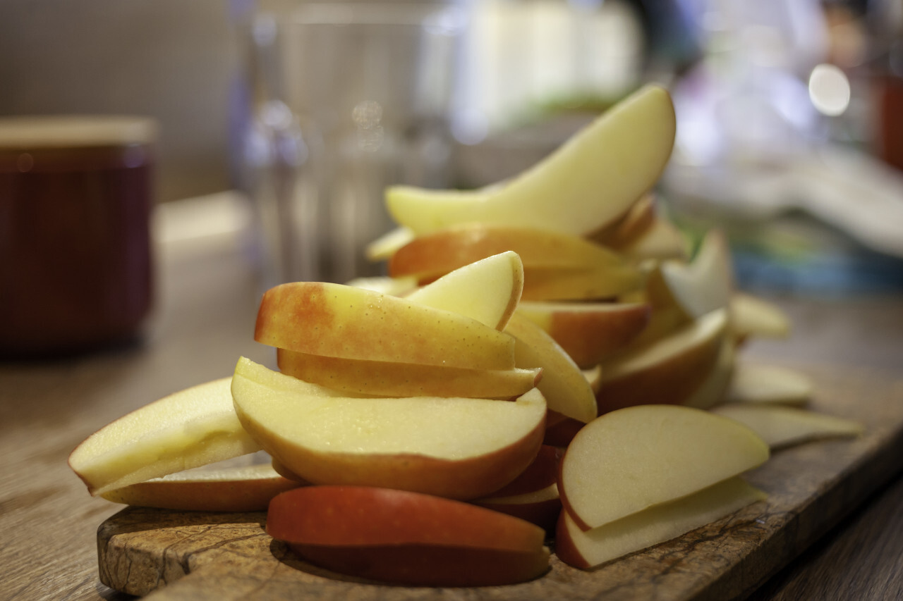 Thin apple slices in a kitchen on a wooden board