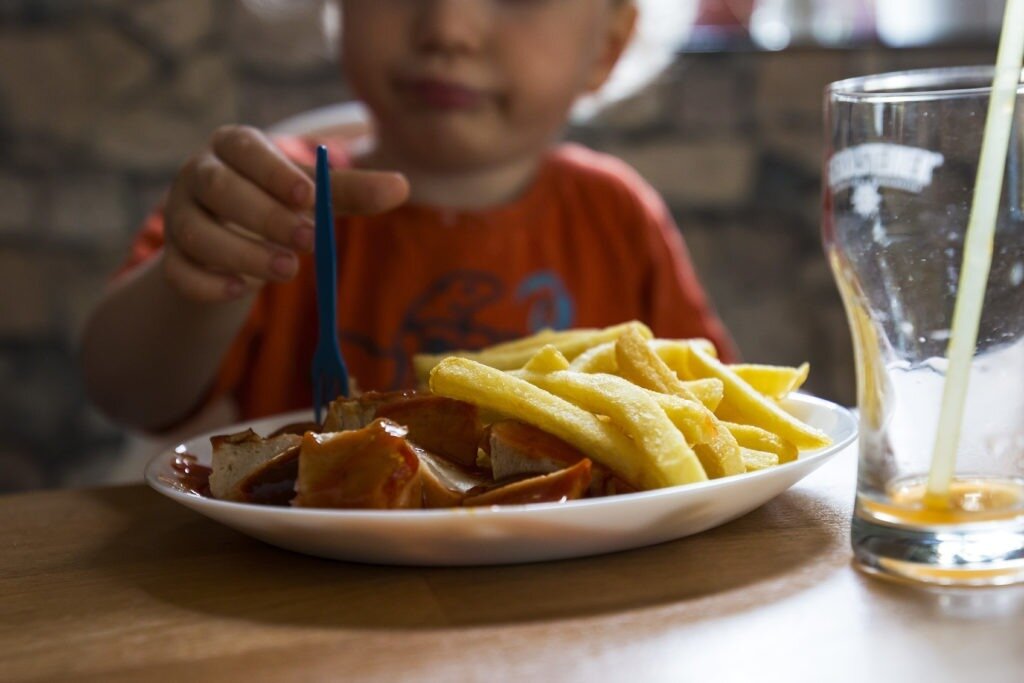 child eats currywurst with chips