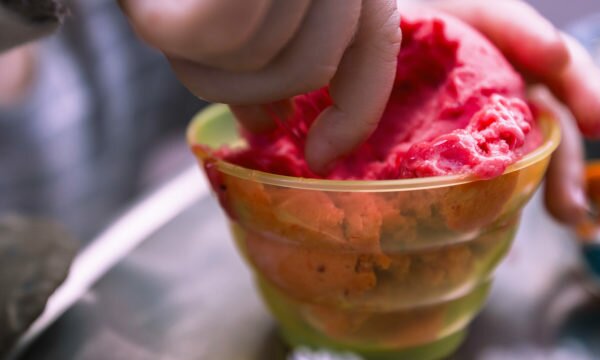 childs hand on strawberry ice cream cup childs hand on strawberry ice cream cup