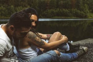 couple is sitting by a lake
